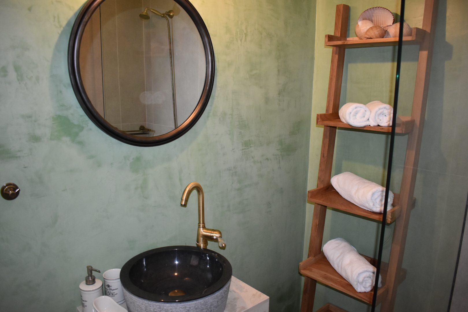 Studio shower room at Perla House with a stone basin, brass tap and towel ladder
