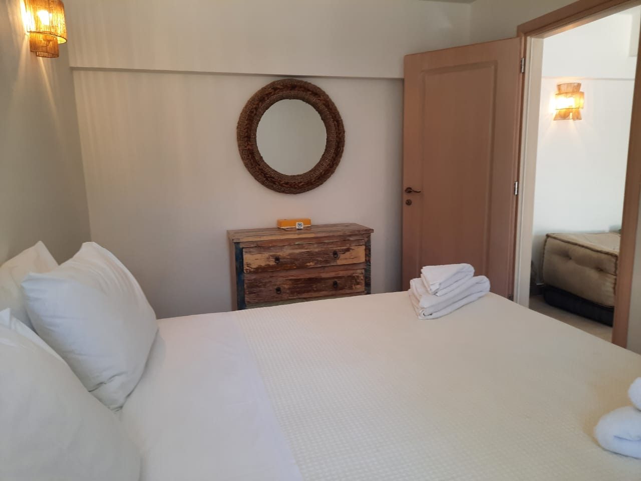 Studio bedroom at Mistral House with a double bed, rattan mirror and fresh towels