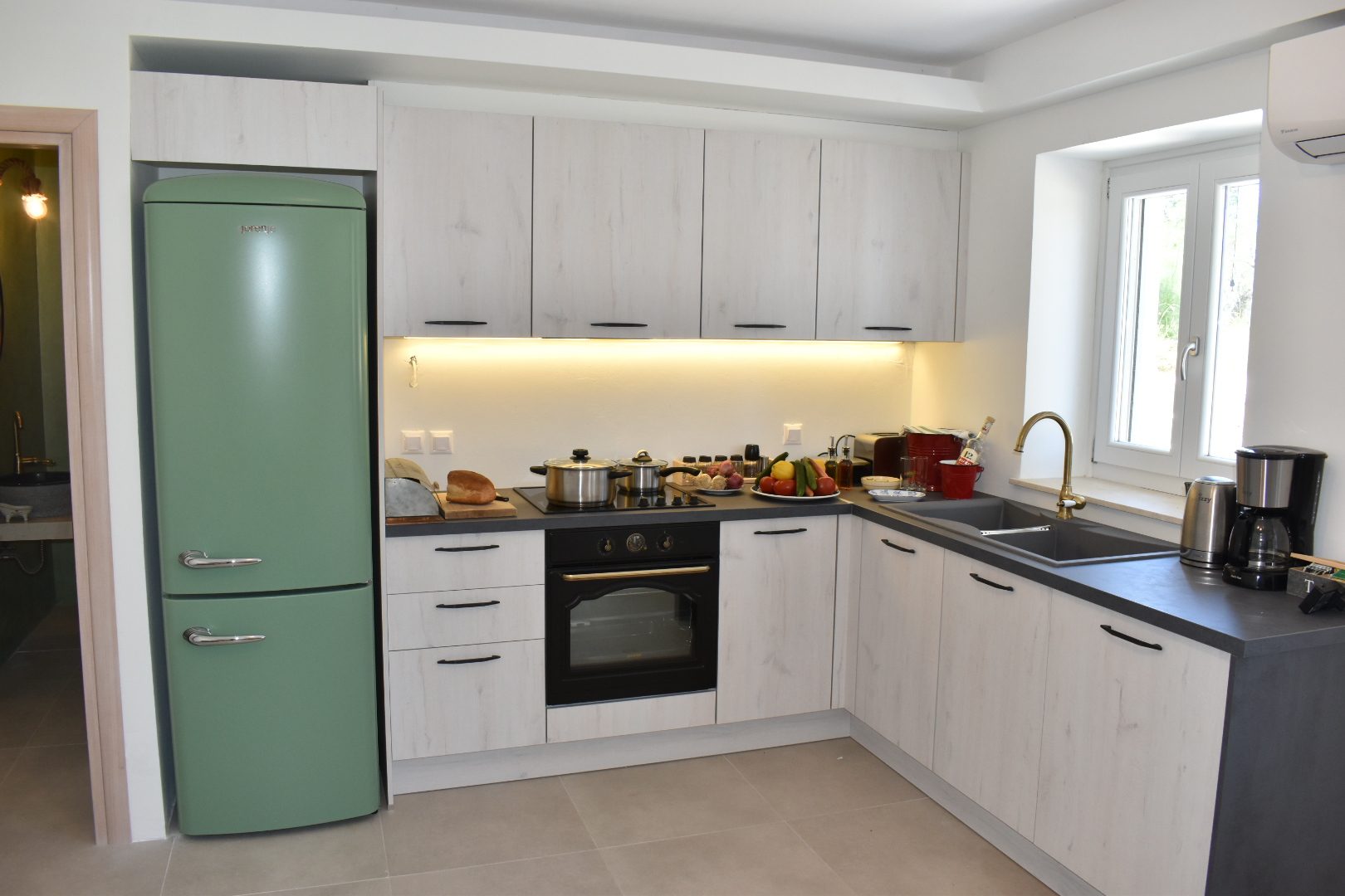 Studio kitchen at Perla House with pale units, dark worktops and a green fridge