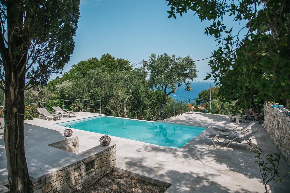 The pool terrace at Perla House shaded by olive trees