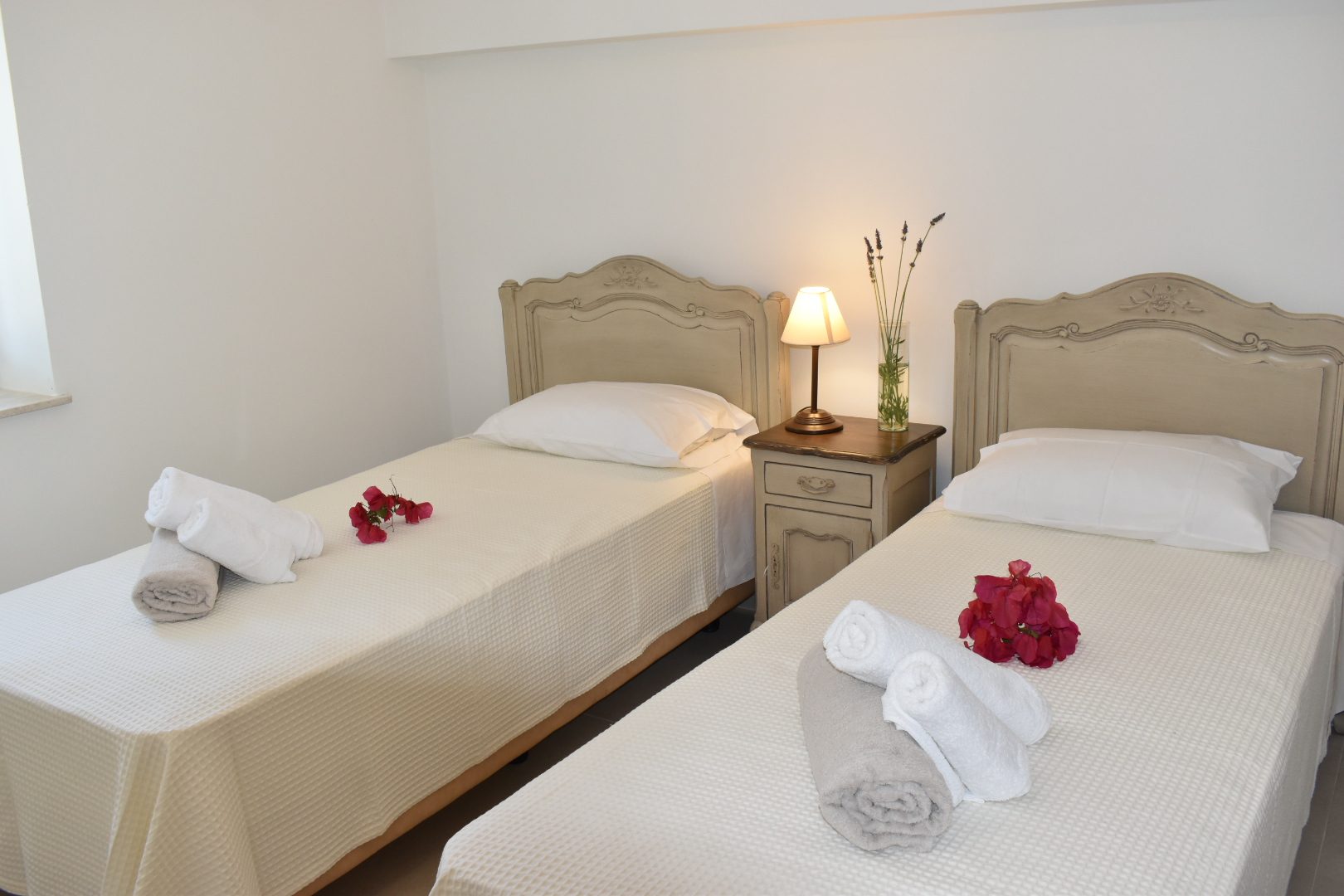 Studio bedroom at Perla House with two beds, fresh towels and bougainvillea