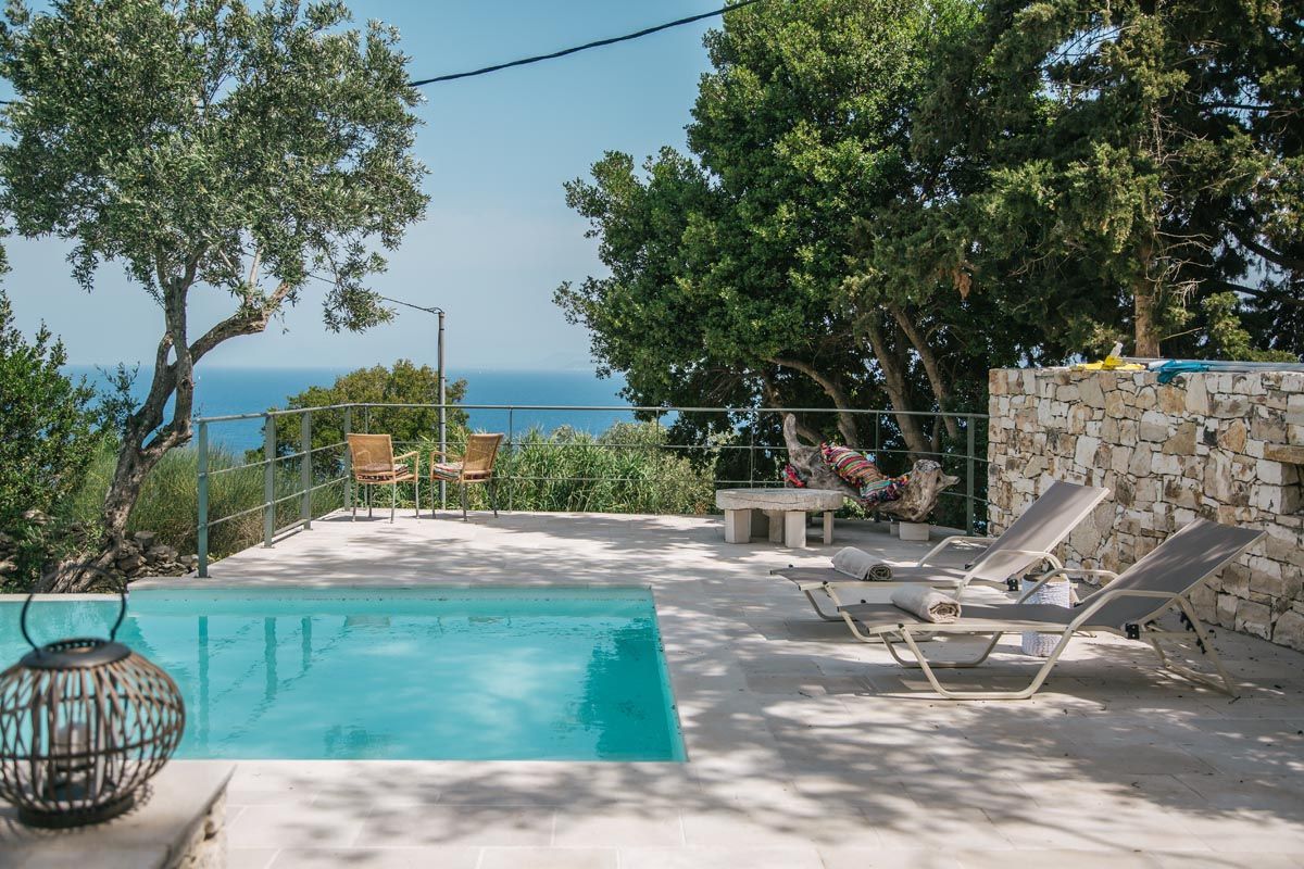 Sun loungers and a hanging chair beside the pool at Perla House