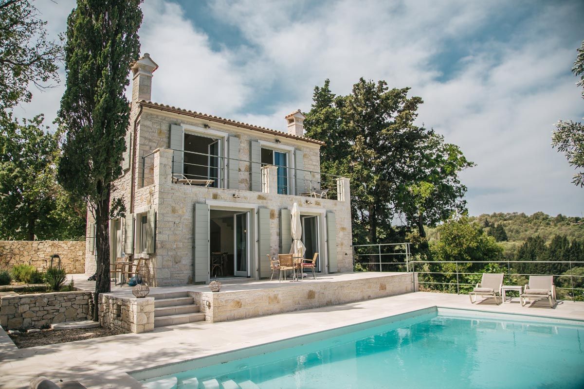 Perla House and its swimming pool framed by cypress trees