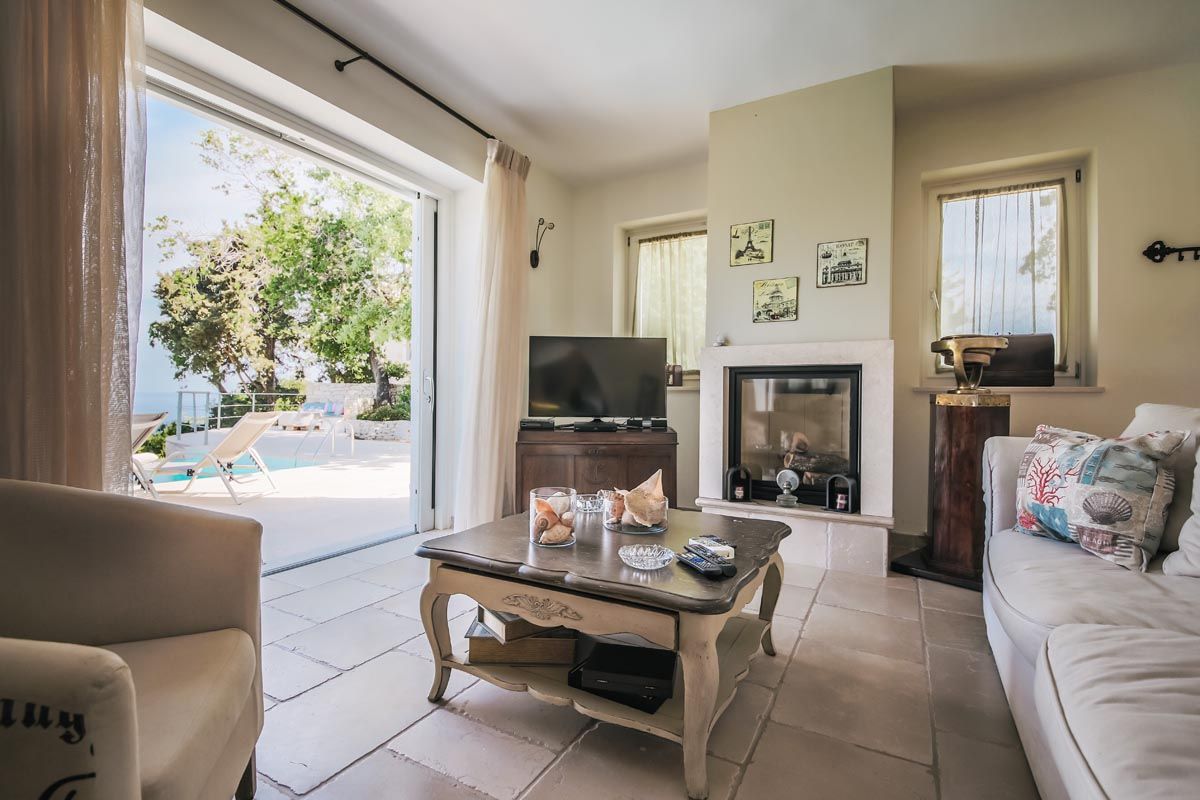 Sitting room at Mistral House with sofas, a fireplace and doors to the terrace