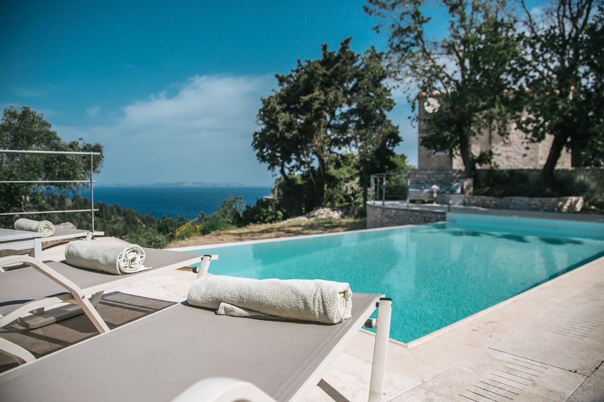 Sun loungers beside the Mistral House pool with the sea beyond