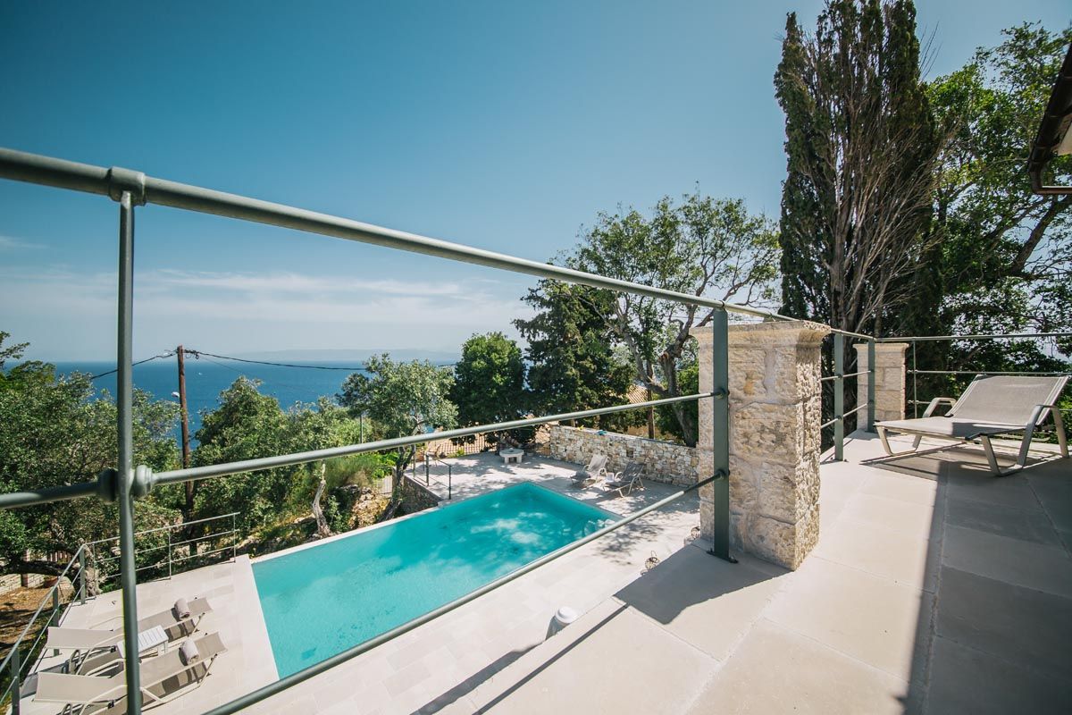 The pool at Perla House with a glass balustrade and a view to the Ionian Sea