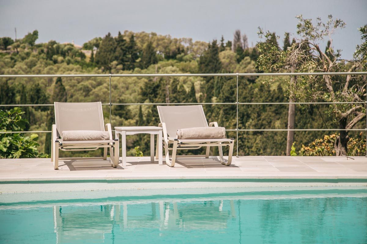 Pair of easy chairs on the Perla House pool terrace overlooking the sea