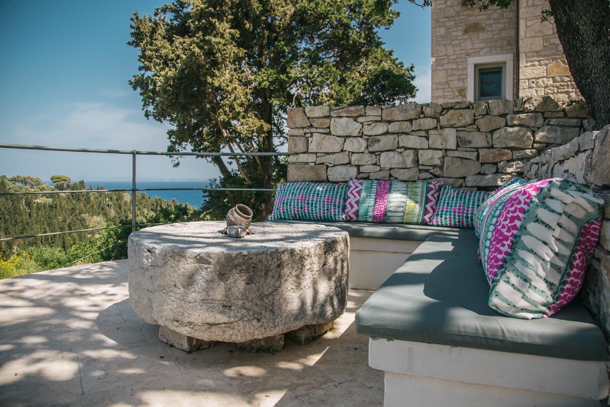 Round stone table and cushioned bench on the shaded terrace at Mistral House